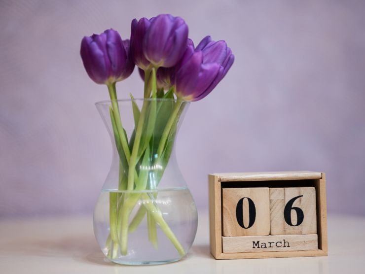 fiori in vaso e calendario in legno con scritto 6 marzo